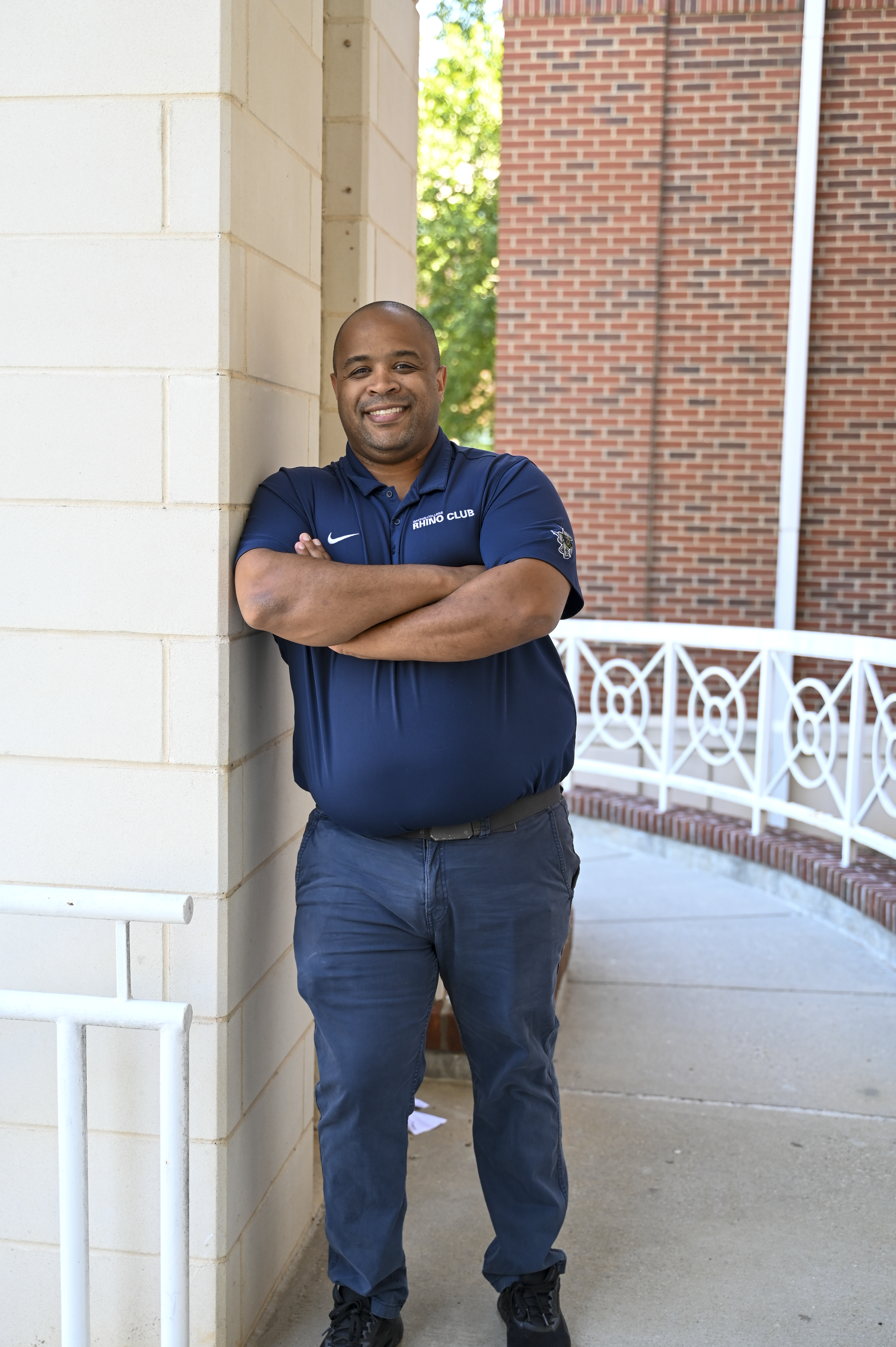 Alumnus Connor leaning against wall and smiling